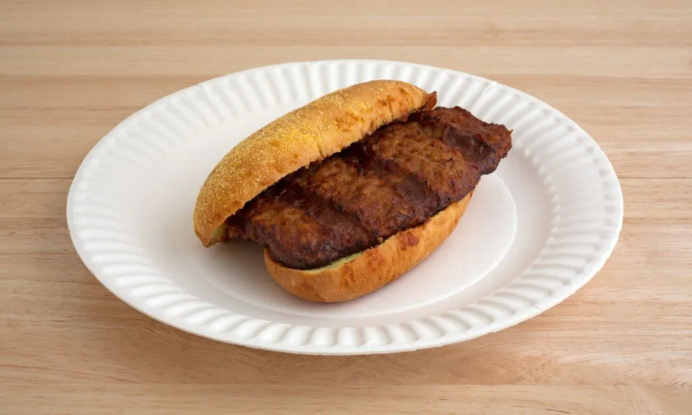 Grilled meat sandwich on a sesame bun, served on a paper plate at Saigon #1, a Vietnamese restaurant in Virginia Beach